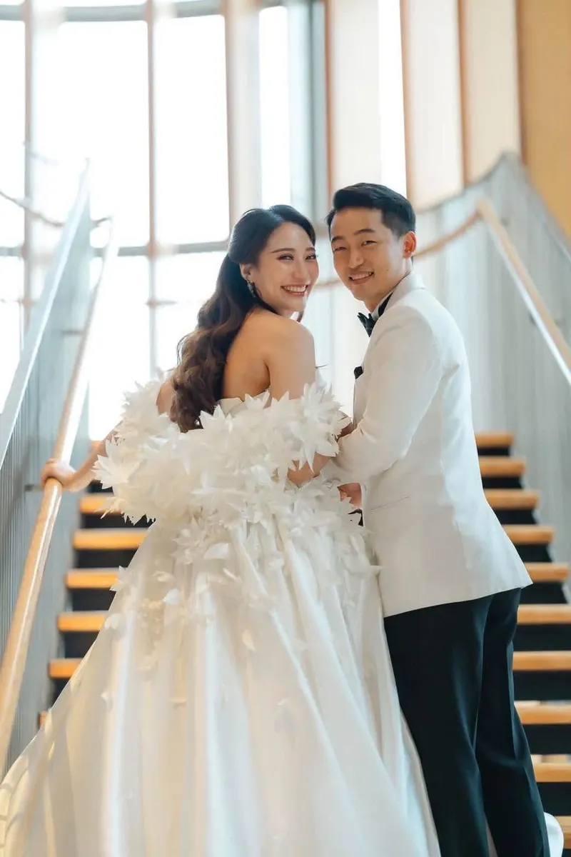 คู่บ่าวสาวบนบันไดกลางแสงแดด เจ้าสาวในเดรสขนนก
